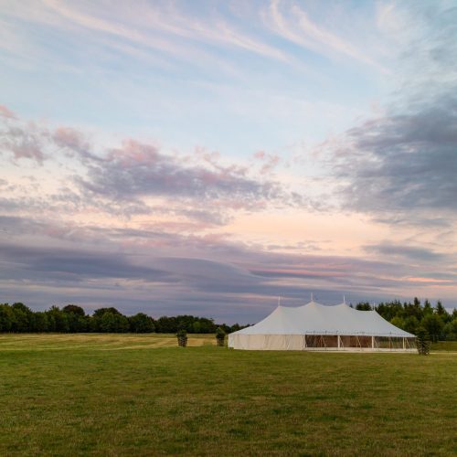 A marquee set up in a field in the evening for an event like a wedding or a party